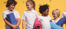 Happy looking school children in front of yellow background