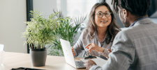People dressed smartly in conversation with one another. A potted plant is on a desk