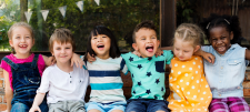 Happy Early Years children sat together with arms round eachother