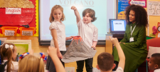 Children displaying model volcano in-front of class
