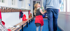 child and man walking up a school corridor