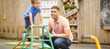 Early Years child on climbing apparatus with adult in attendance 