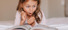 Girl reading a book. She looks excited.