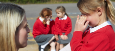 Adult talking to a girl in a red uniform with two others in the background
