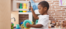 Child playing with a toy microwave and pot