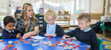 Teacher with Early Years children round blue table