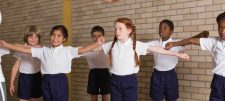 School children with arms out stretched to the side