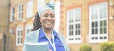Term Times - summer 2025: Why headteacher coaching matters Lady smiling and wearing blue, infront of building