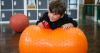Boy on orange inflatable toy holding a toy bus