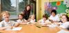 Teacher and children sitting around a school desk