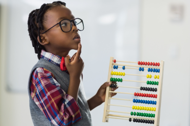 Child with finger on chin, holding abacus and looking at wall