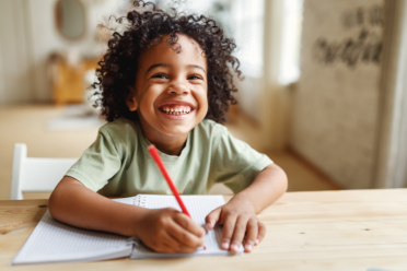 Happy child holding pencil on paper