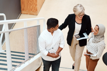 Three people talking next to a flight of stairs